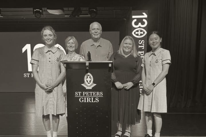 Students and staff from St Peter's Girls' School on stage with a Lisa Fahey Foundation banner